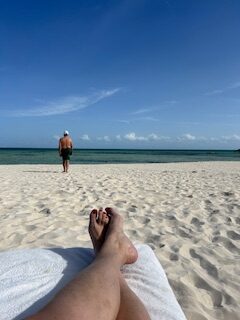 Person relaxing while watching gentle waves at a beach in the El Dorado Maroma adult-only resort