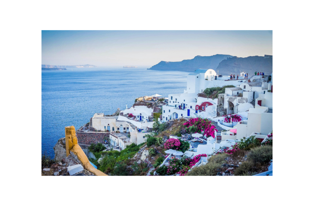 Santorini caldera view with white-washed cliffside buildings, pink bougainvillea, and the Aegean Sea in Oia, Greece