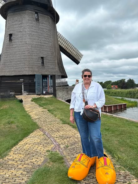 Traveler in wooden clogs beside a historic Dutch windmill on a Rhine river cruise excursion