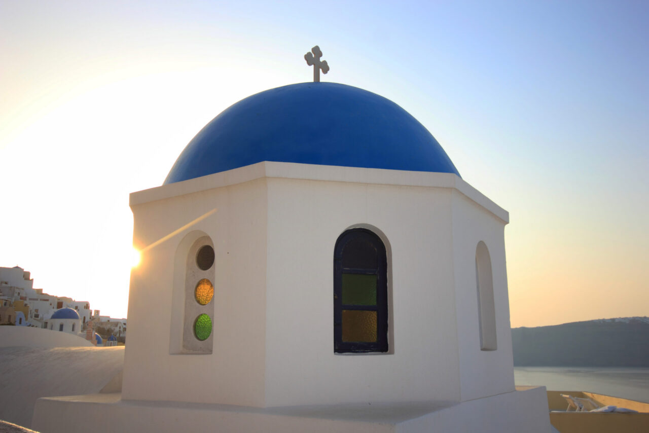 Traditional Greek Orthodox white church with a blue dome and cross in the village of Oia, Santorini, Greece