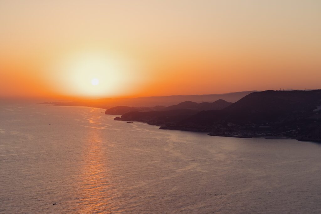 Golden hour sunset over the Aegean Sea and Santorini coastline, the view that defines where to stay in Santorini Greece