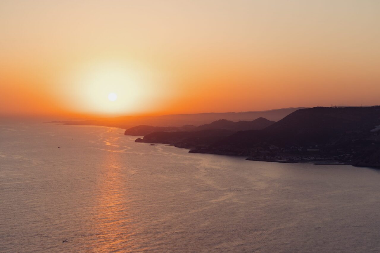 Golden hour sunset over the Aegean Sea and Santorini coastline, the view that defines where to stay in Santorini Greece