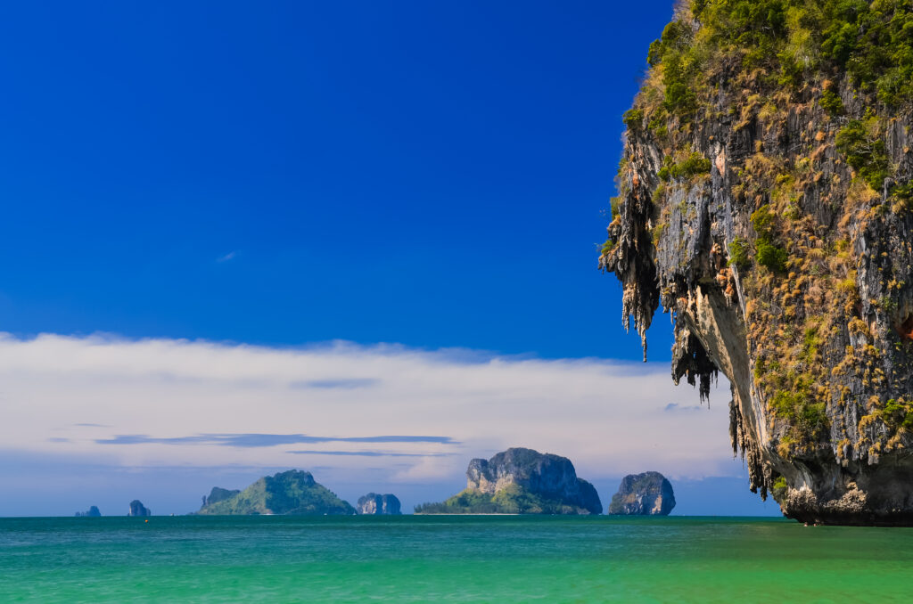 Turquoise water beneath towering limestone cliffs draped in greenery