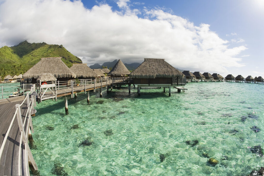 Thatched overwater bungalows resting above a clear turquoise coral lagoon