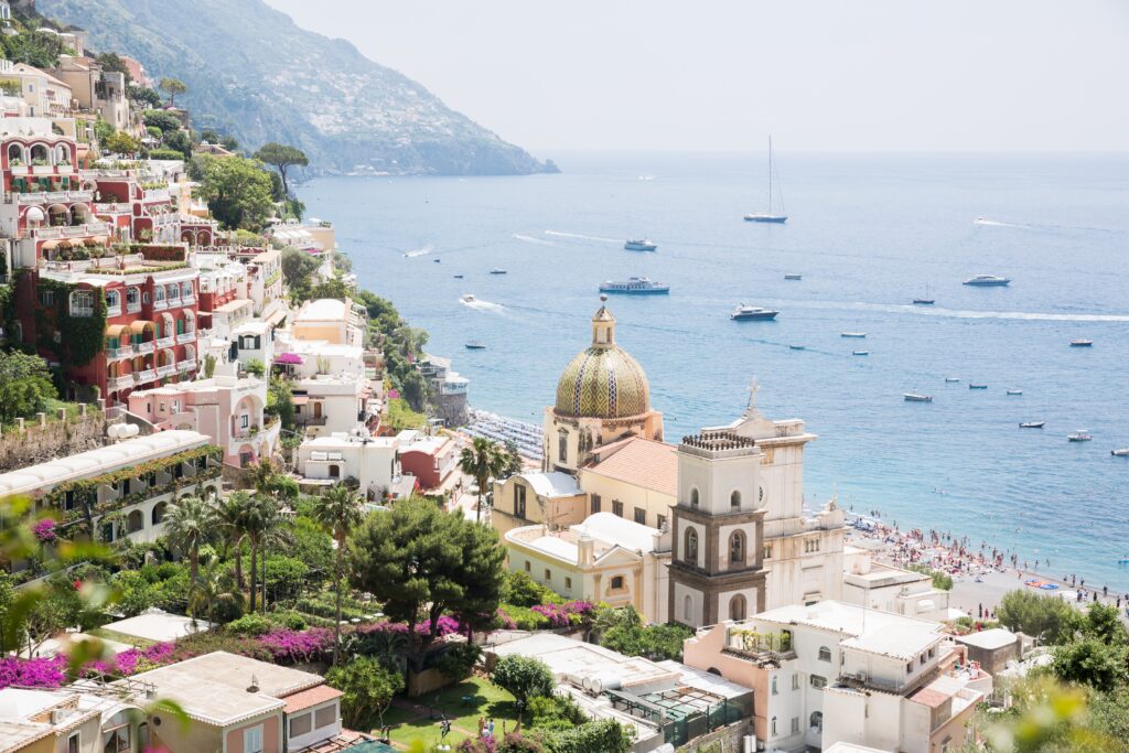 Amalfi Coast town with a domed church and boats moored in the bay below pastel houses