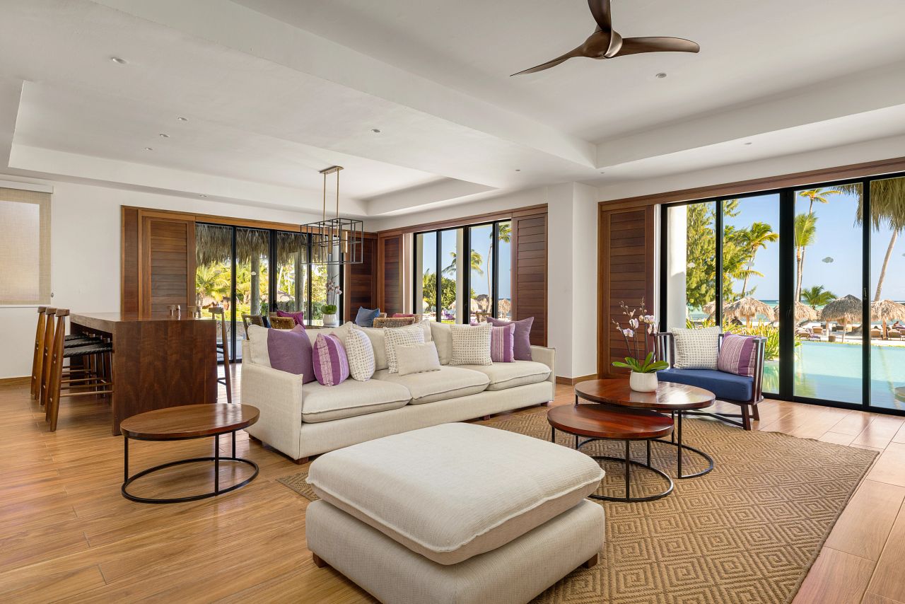 Preferred Club Presidential Suite living room at Secrets Cap Cana with a bar, dining area and sliding glass on two sides opening to the pool