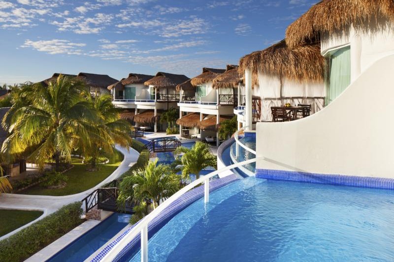 Palapa-roofed swim-up suites around a curved pool at El Dorado Casitas Royale