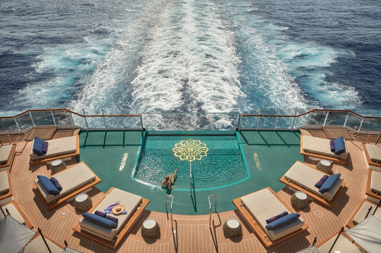 Aft pool and teak sun deck on an Explora Journeys luxury small ship, with the ship's wake stretching behind